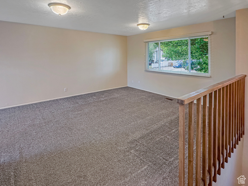 Carpeted spare room featuring baseboards and a textured ceiling