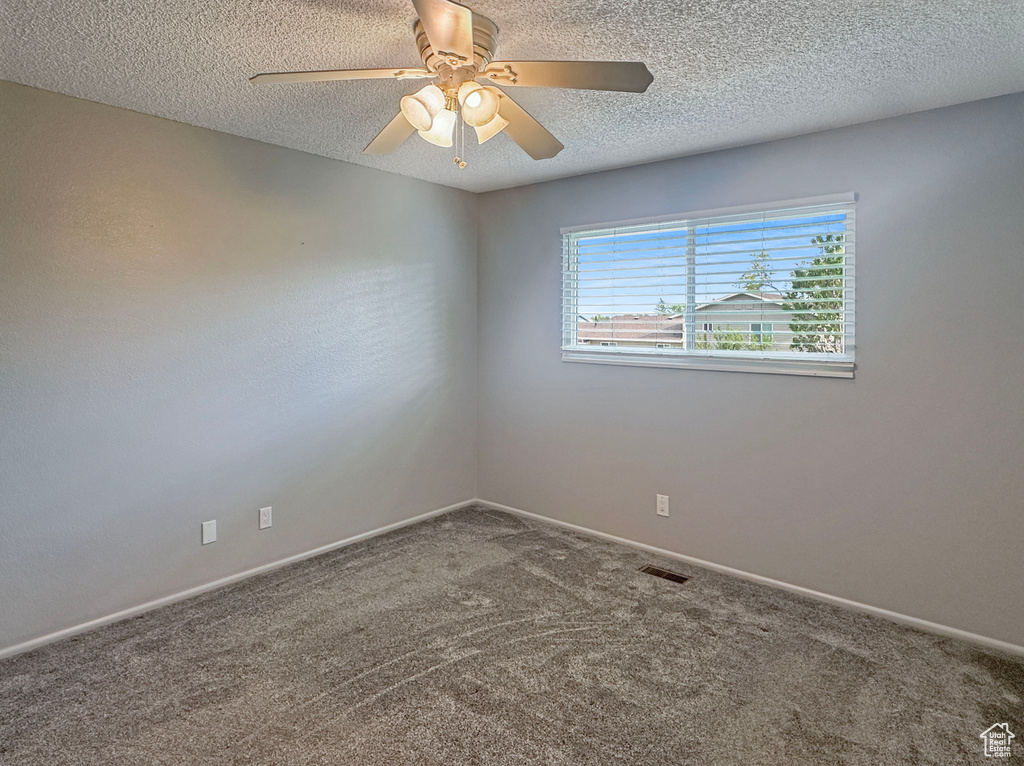Spare room featuring carpet flooring, ceiling fan, a textured ceiling, and baseboards