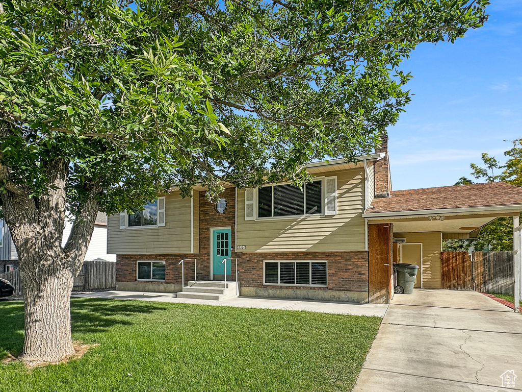 View of front facade featuring driveway, a carport, a chimney, and brick siding