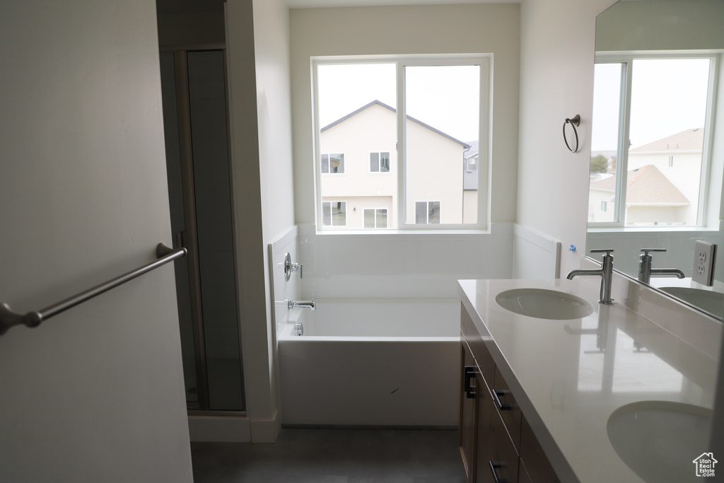 Bathroom with double vanity, a bath, and a stall shower