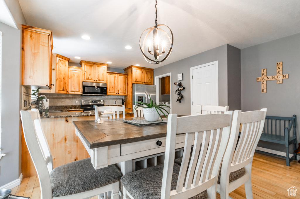 Dining room with a chandelier, light wood-type flooring, recessed lighting, and baseboards