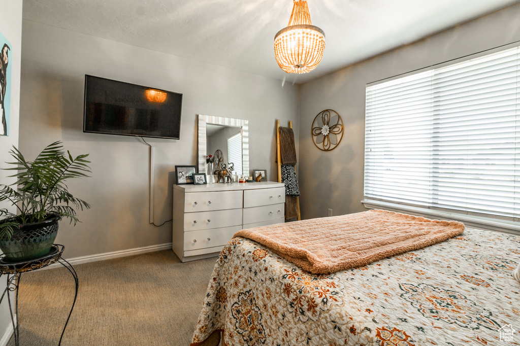 Carpeted bedroom featuring a chandelier and baseboards