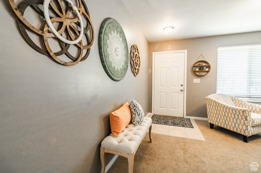 Tiled foyer entrance with baseboards and carpet