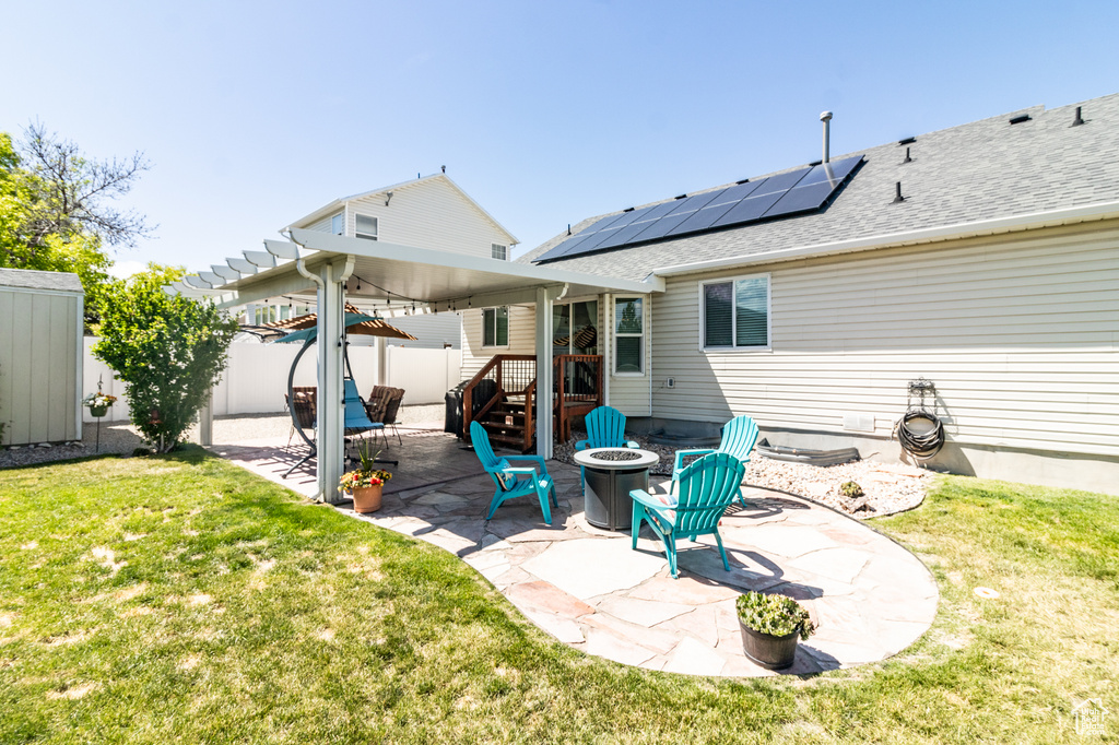 Rear view of property featuring a patio, a fire pit, and solar panels