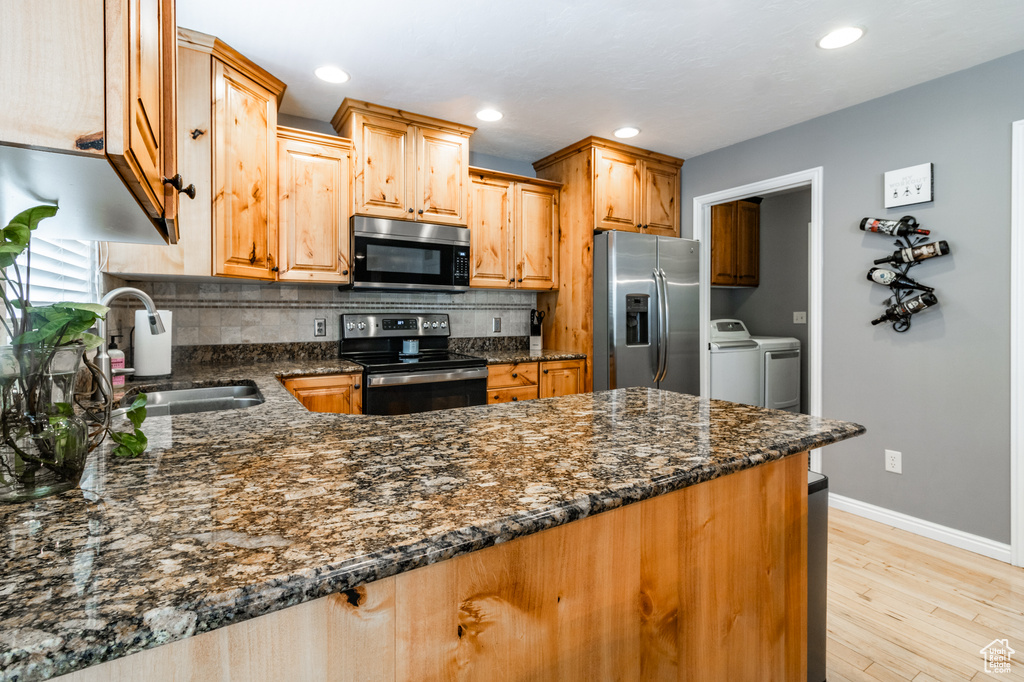 Kitchen featuring stainless steel appliances, a sink, separate washer and dryer, decorative backsplash, and recessed lighting