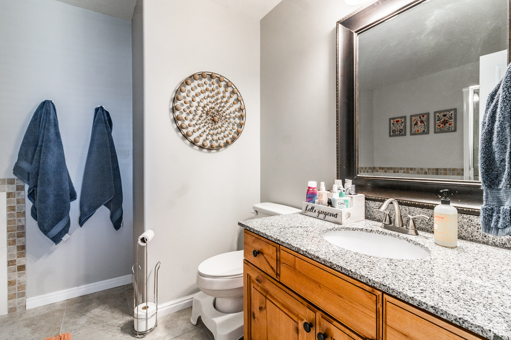 Bathroom featuring toilet, vanity, tile patterned flooring, and baseboards