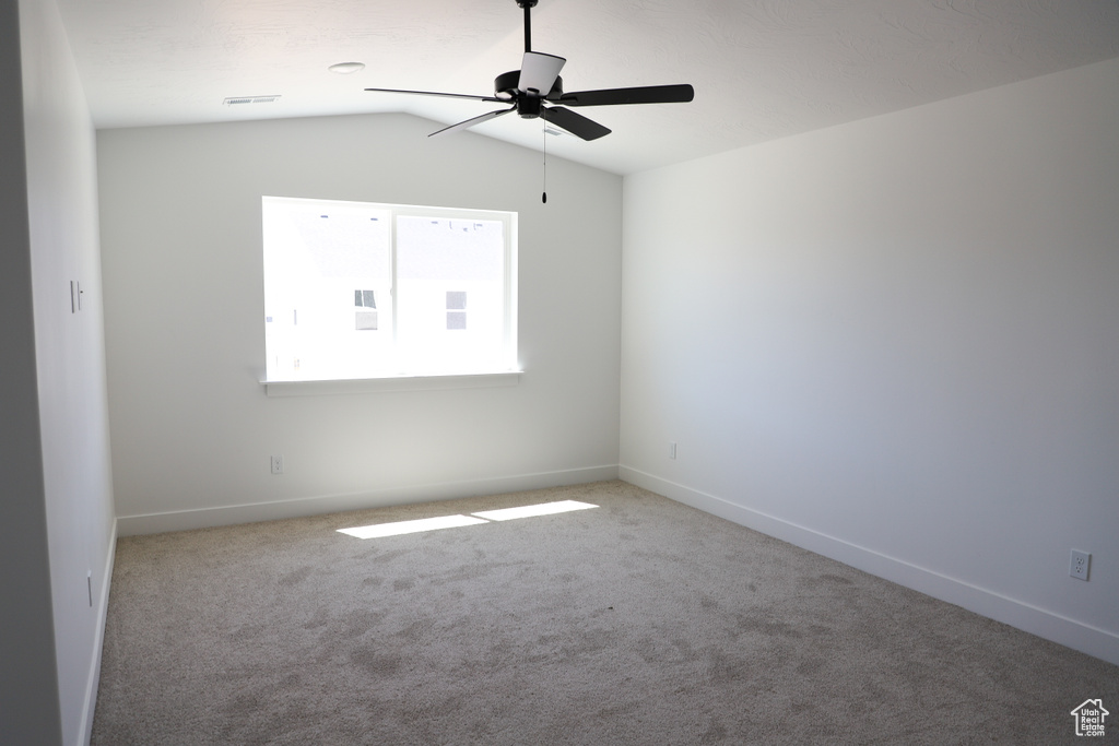 Spare room featuring ceiling fan, carpet flooring, baseboards, and lofted ceiling