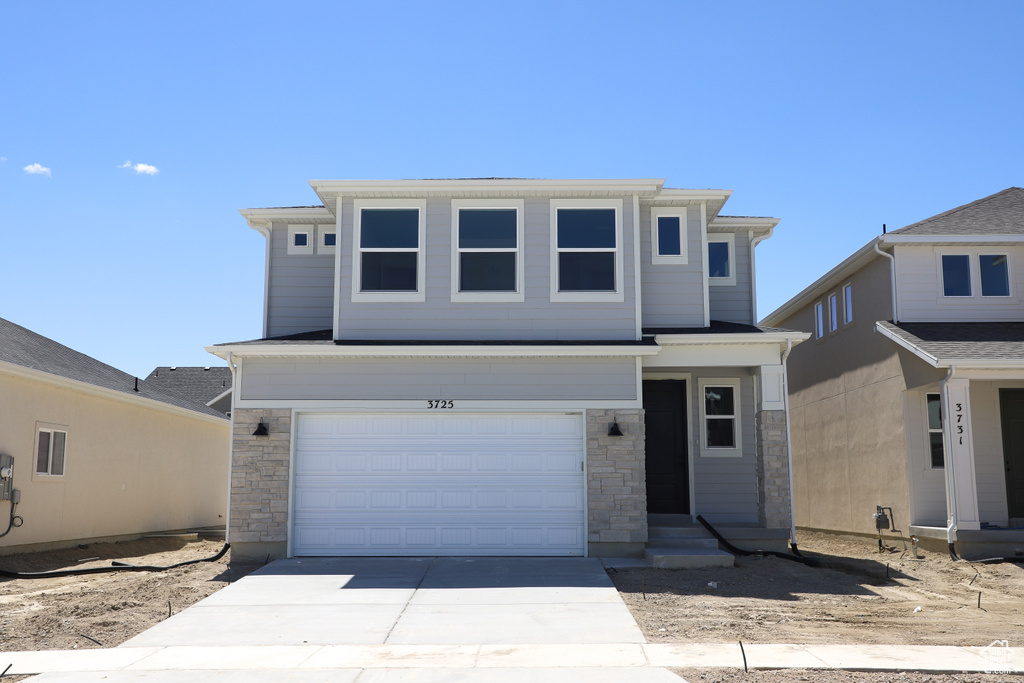View of front of property with stone siding, driveway, and a garage