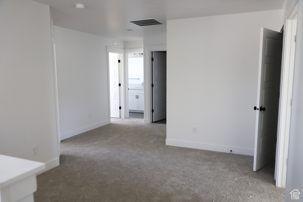Carpeted spare room featuring baseboards and a smoke detector