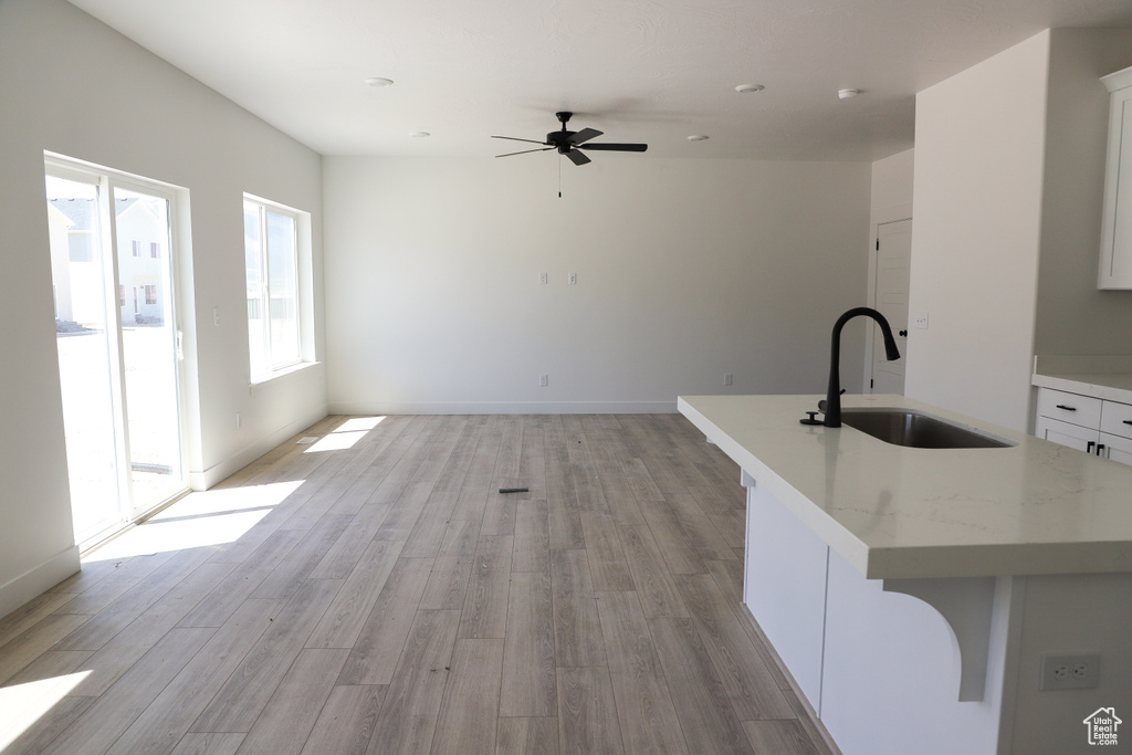 Unfurnished living room with a sink, light wood-style flooring, and a ceiling fan