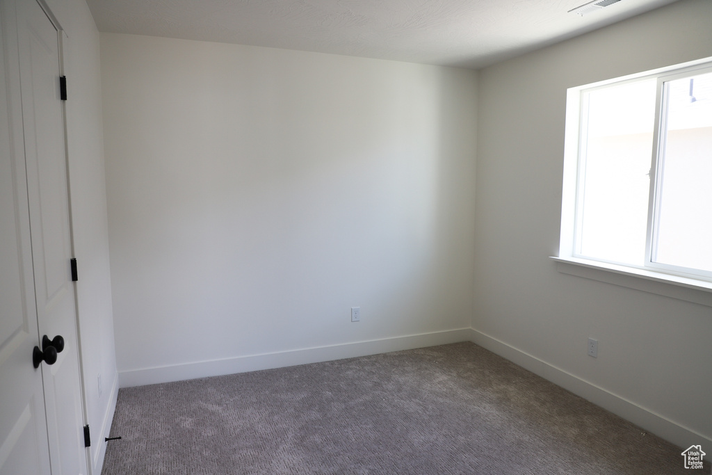 Carpeted spare room featuring baseboards