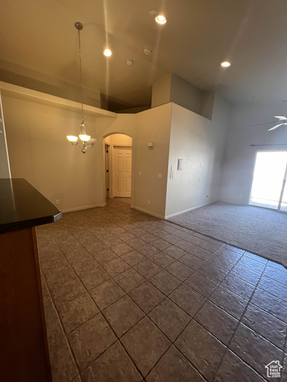 Spare room with arched walkways, baseboards, recessed lighting, dark colored carpet, and a chandelier