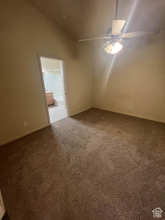 Carpeted empty room featuring lofted ceiling, baseboards, and a ceiling fan