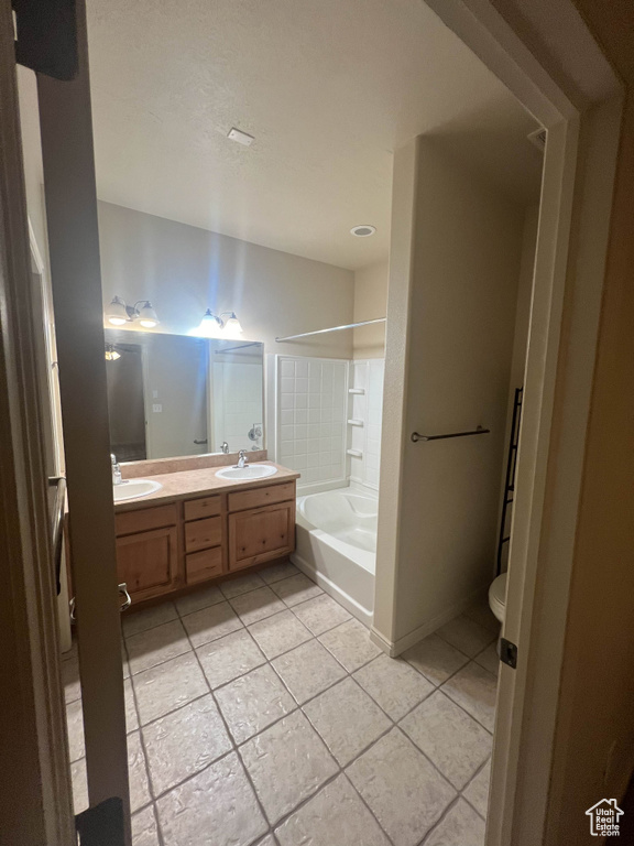 Full bathroom with tile patterned floors, double vanity, washtub / shower combination, and toilet