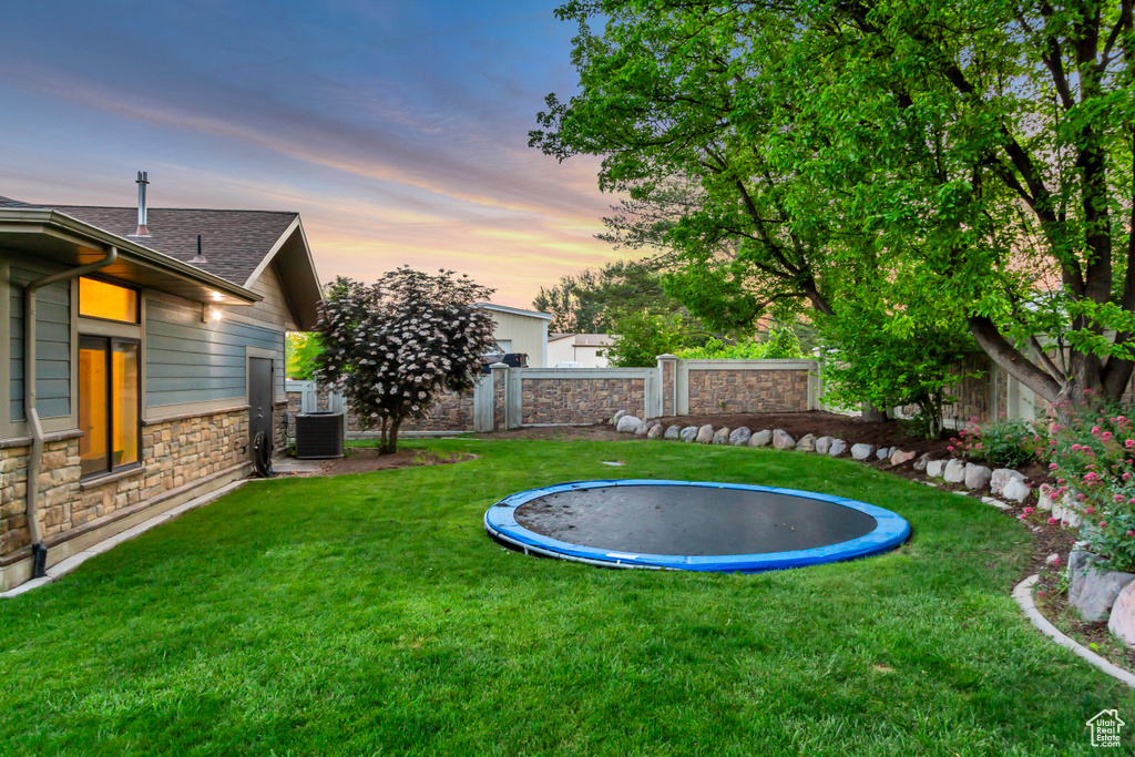 Yard at dusk with a trampoline and central AC