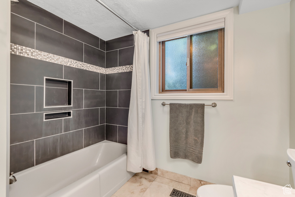 Bathroom featuring toilet, tile patterned flooring, shower / bath combo, vanity, and a textured ceiling