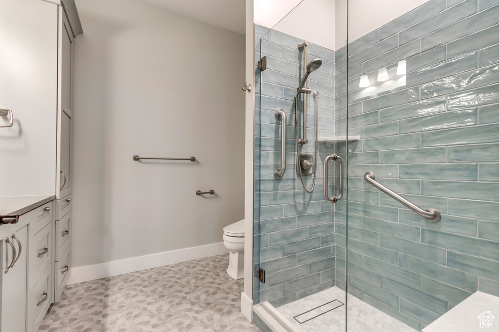 Full bathroom featuring a shower stall, baseboards, and toilet
