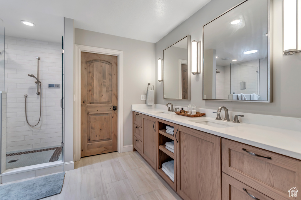 Full bathroom featuring double vanity, a stall shower, baseboards, and recessed lighting