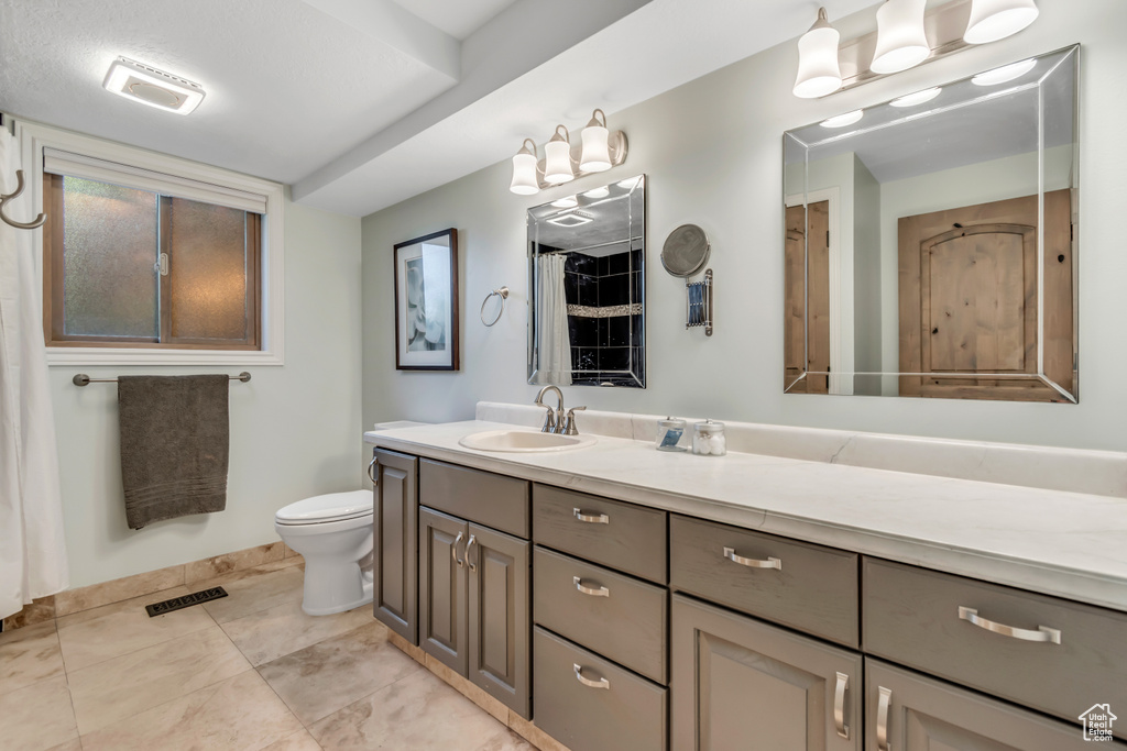 Bathroom with vanity, toilet, baseboards, and tile patterned flooring