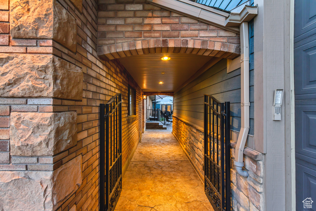 Hallway with arched walkways, wooden walls, and light stone finish flooring