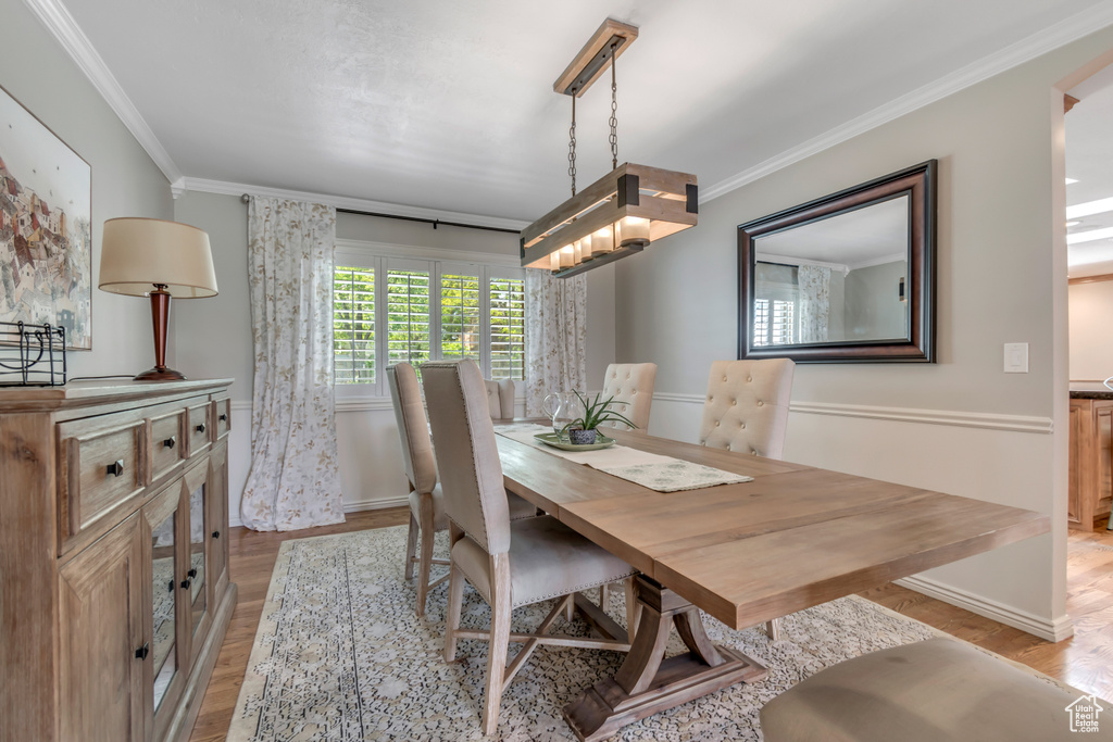 Dining area with light wood-type flooring, crown molding, and baseboards