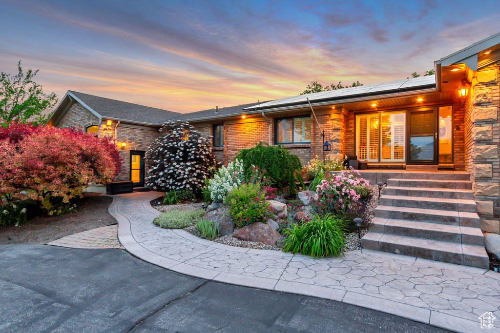 View of front of house featuring solar panels, brick siding, and a porch