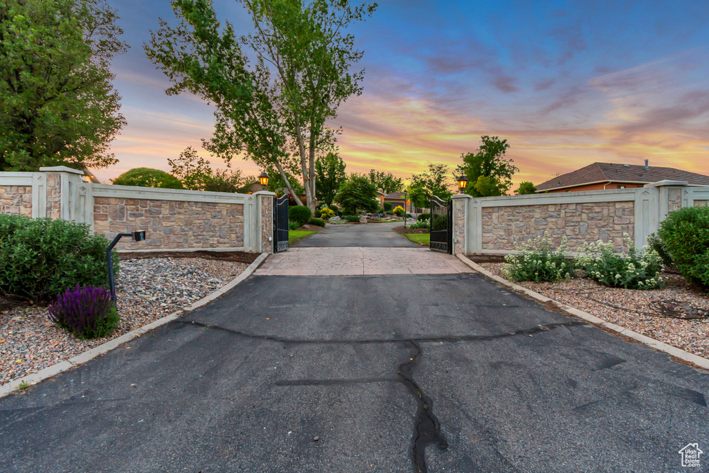 View of asphalt driveway with a gate and a gated entry