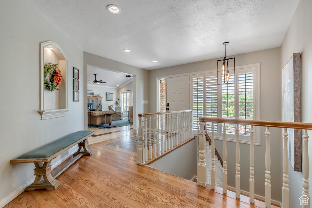 Hall with an upstairs landing, plenty of natural light, wood finished floors, baseboards, and recessed lighting