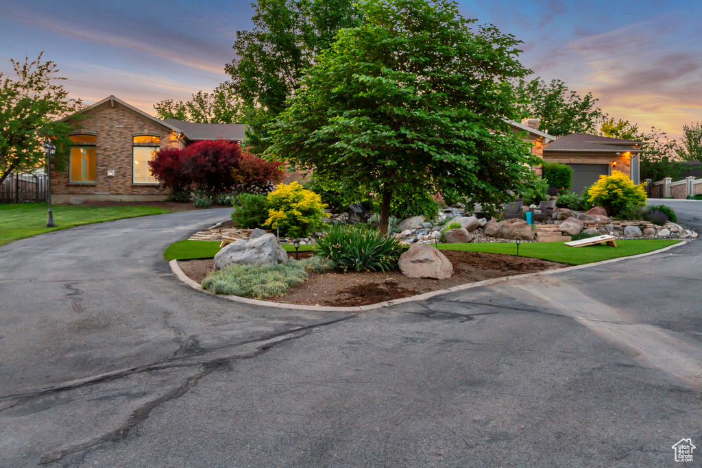 Obstructed view of property with curved driveway and brick siding