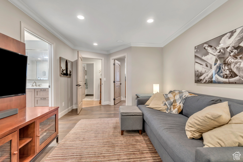 Living room with recessed lighting, light wood-style floors, crown molding, and baseboards