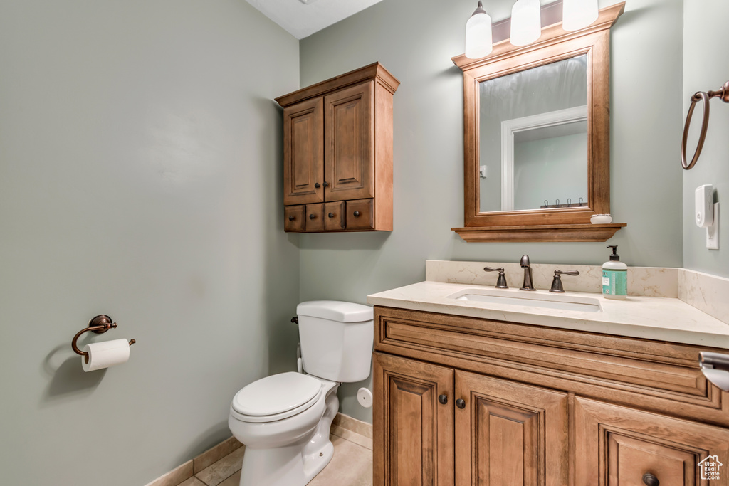 Bathroom featuring toilet, vanity, baseboards, and tile patterned flooring