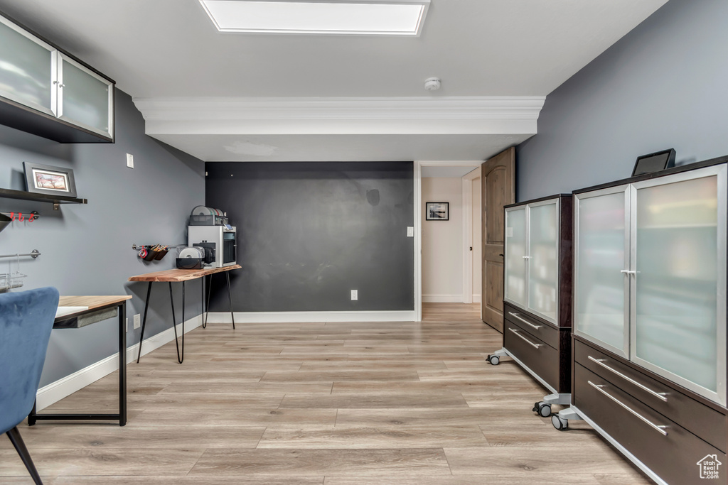 Office area with light wood-type flooring, baseboards, and ornamental molding
