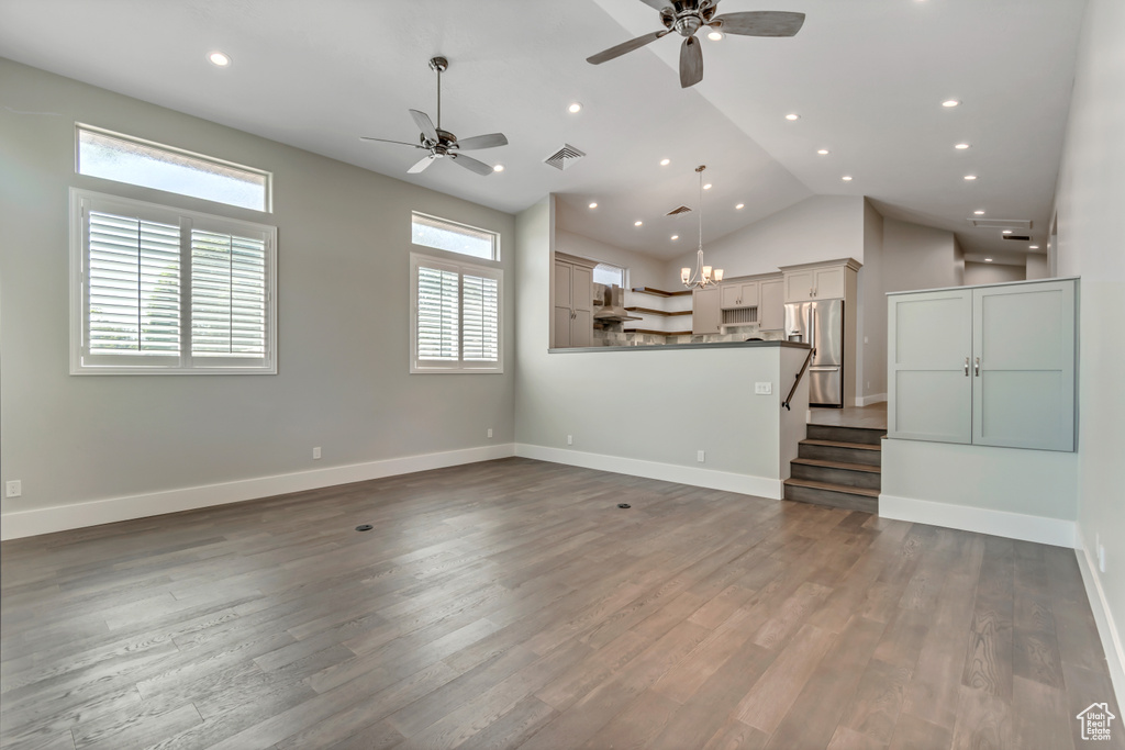 Unfurnished living room with ceiling fan, wood finished floors, recessed lighting, baseboards, and high vaulted ceiling