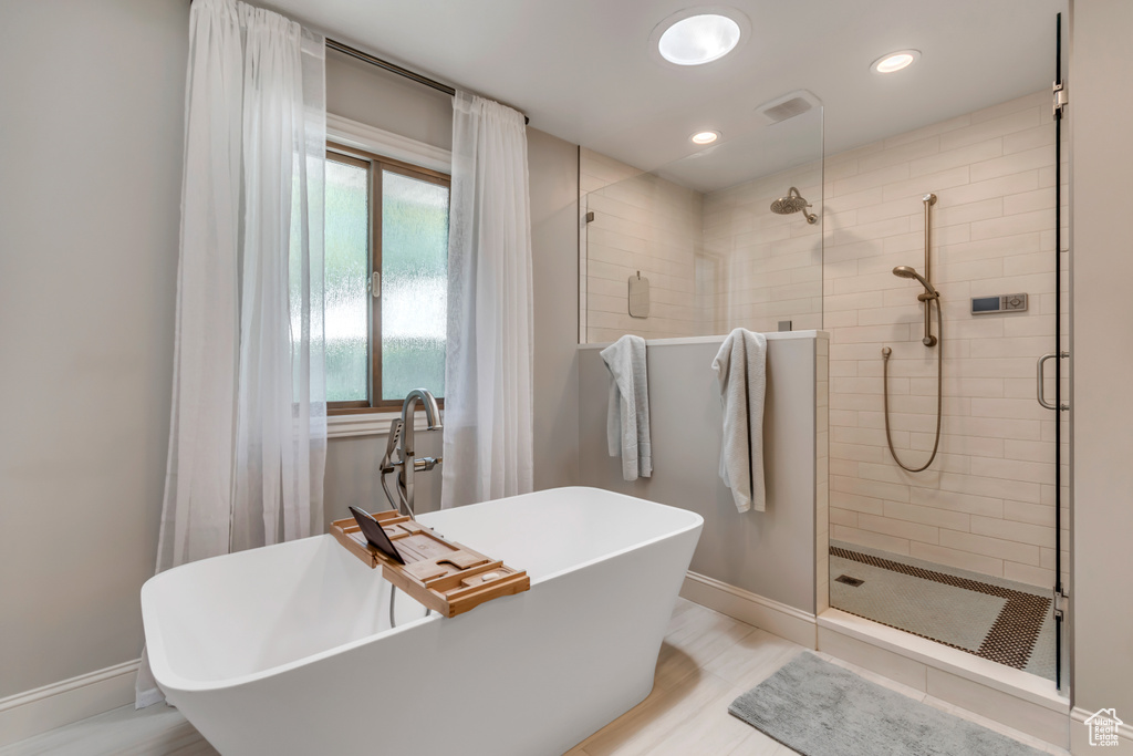 Full bathroom with a stall shower, a freestanding tub, baseboards, and recessed lighting