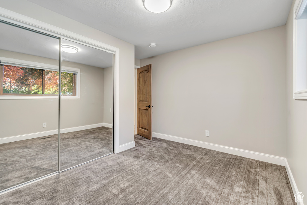 Unfurnished bedroom with a closet, carpet, and baseboards