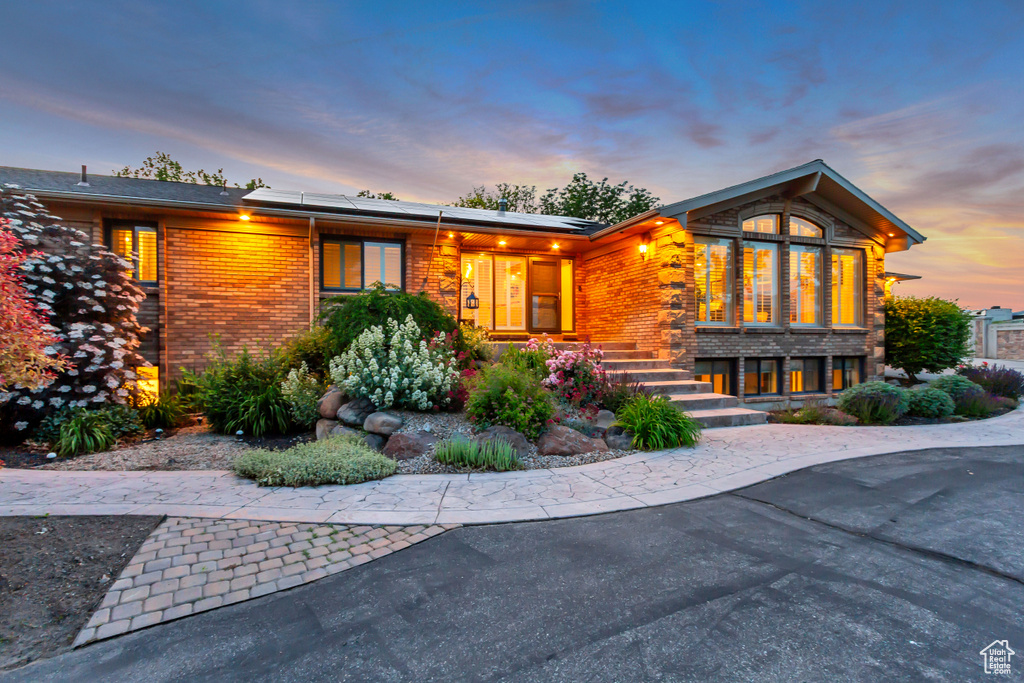 View of front of house featuring roof mounted solar panels and brick siding