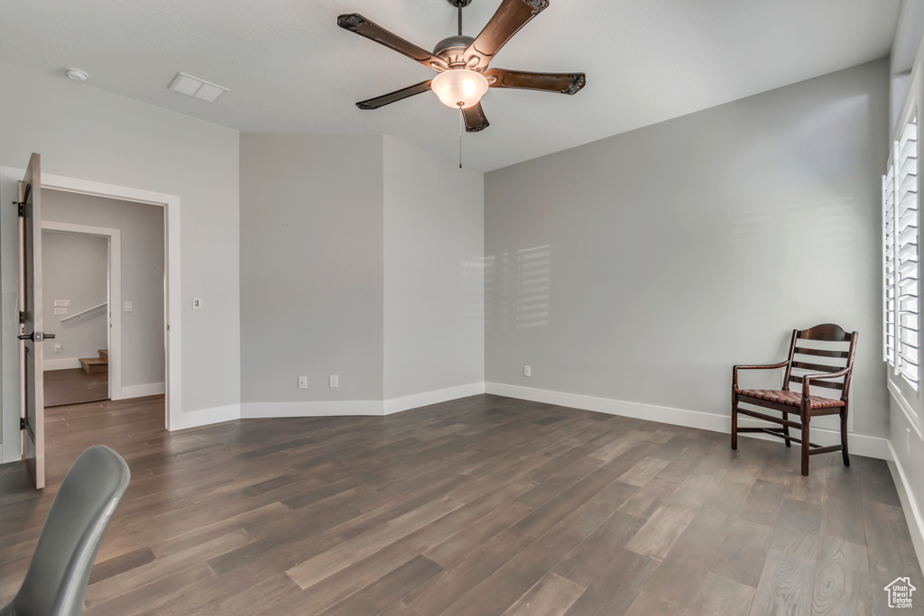 Empty room with ceiling fan, dark wood-style floors, baseboards, and a smoke detector