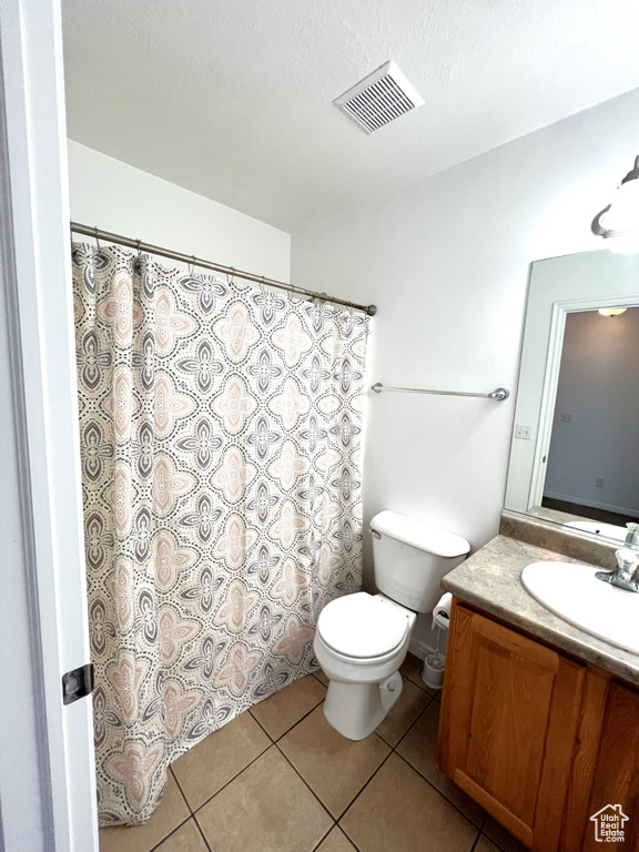 Bathroom featuring toilet, tile patterned floors, and vanity