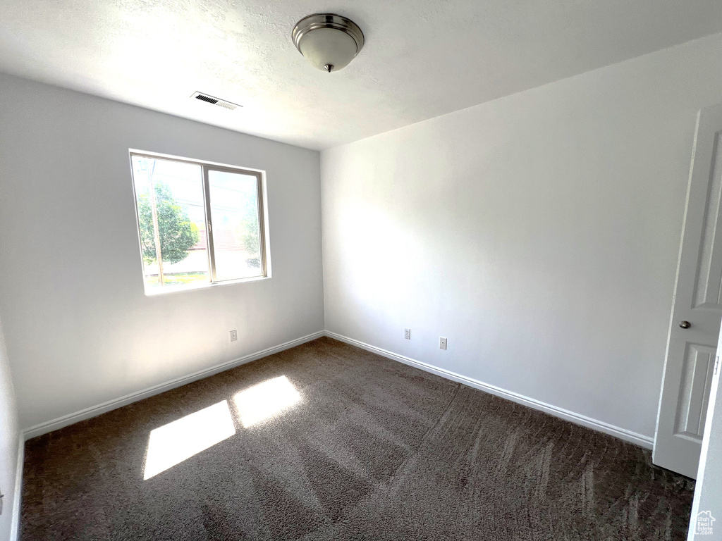 Empty room with dark carpet and baseboards