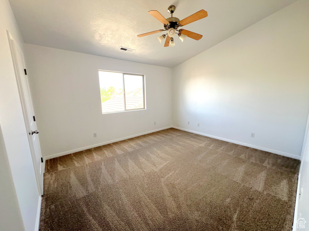 Carpeted spare room with baseboards, ceiling fan, and vaulted ceiling