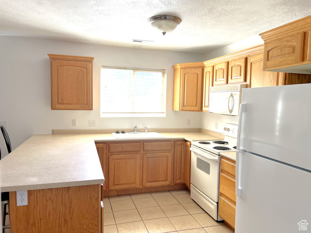 Kitchen featuring white appliances, a sink, a peninsula, light countertops, and a textured ceiling