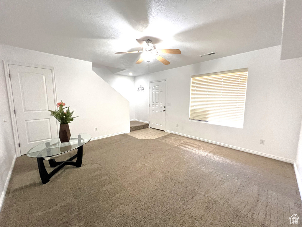 Carpeted spare room featuring a ceiling fan and baseboards