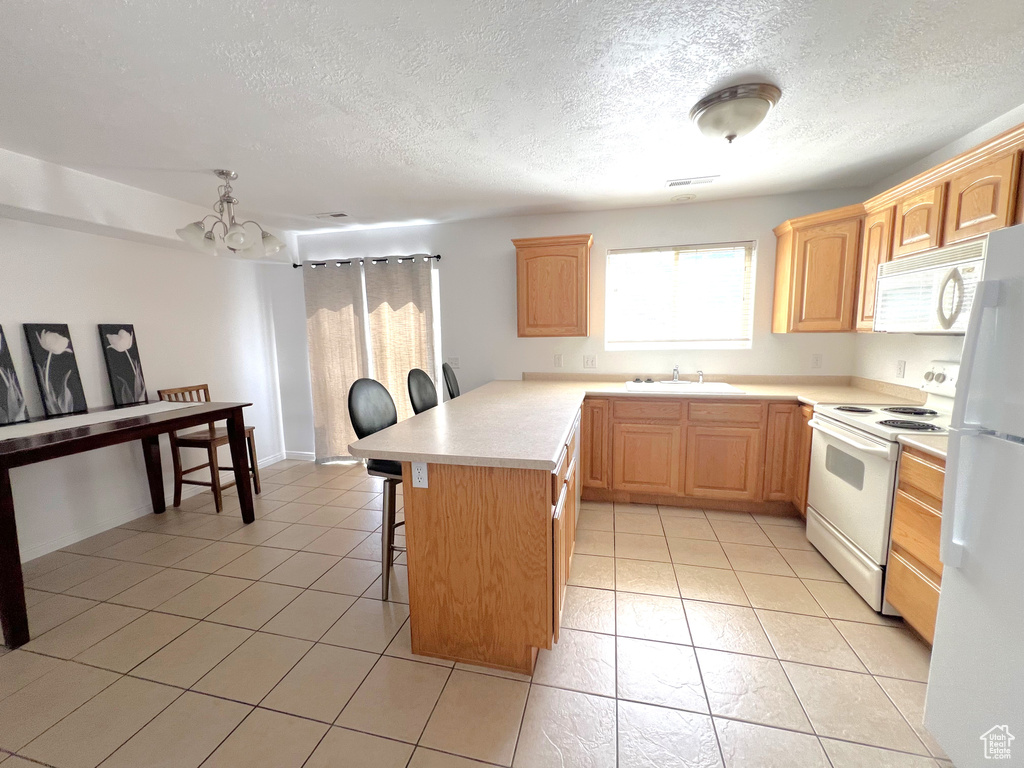 Kitchen featuring white appliances, a sink, a breakfast bar area, a peninsula, and light countertops