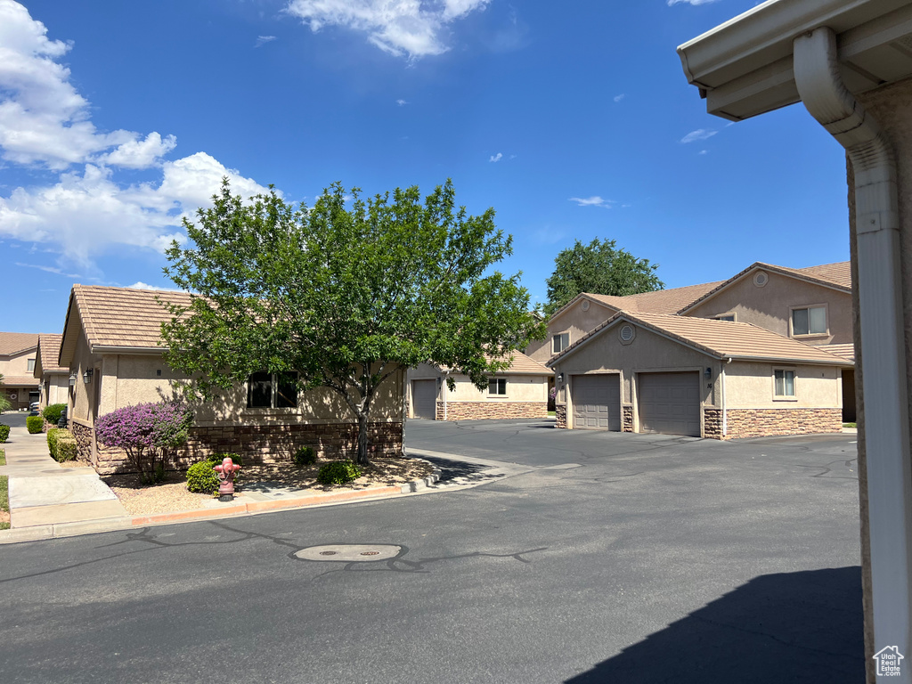 View of front of house featuring stucco siding, a garage, a tile roof, and driveway