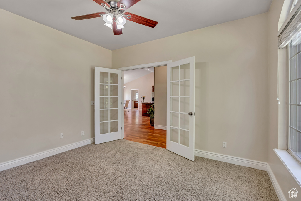 Carpeted empty room featuring french doors, baseboards, and ceiling fan