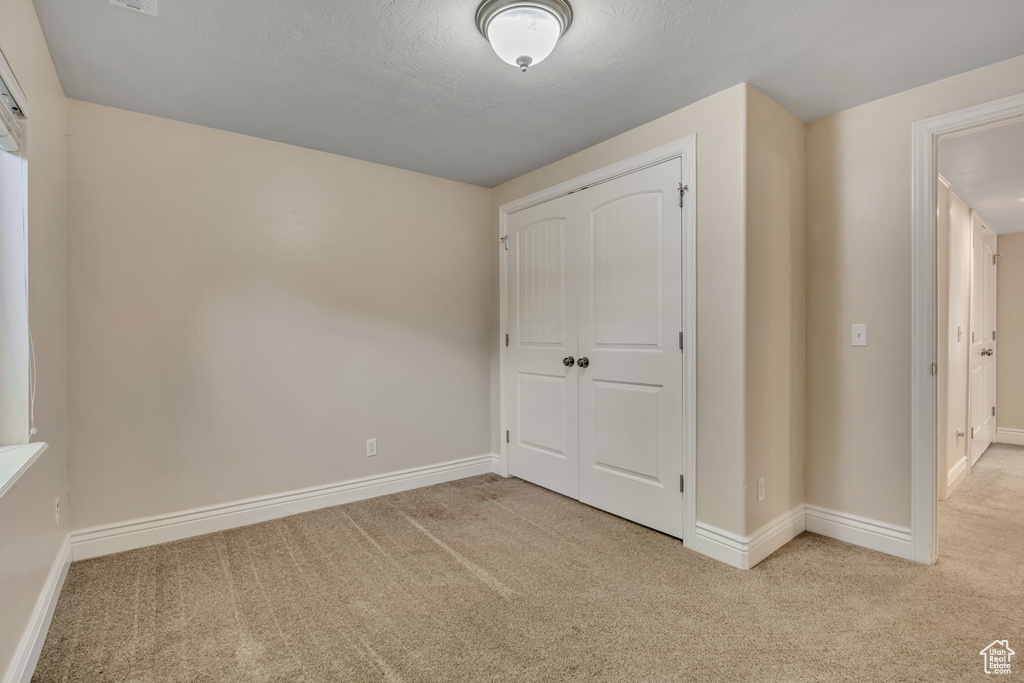 Unfurnished bedroom with carpet flooring, baseboards, and a closet