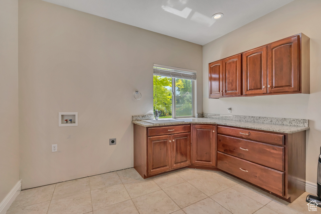 Kitchen featuring a sink, light tile patterned floors, and brown cabinets