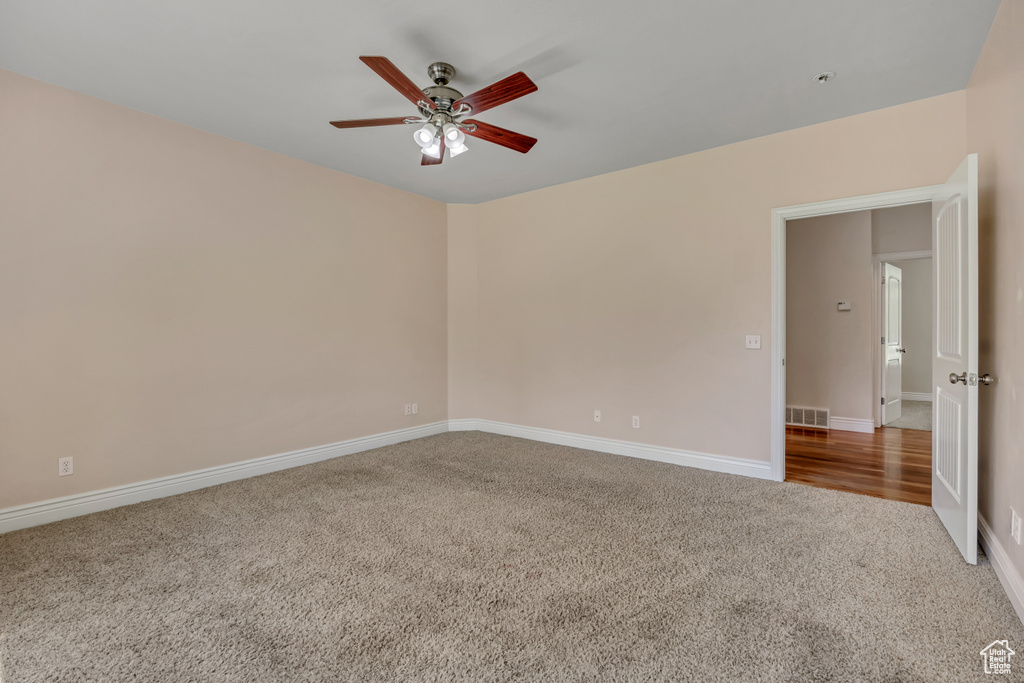Empty room with carpet, a ceiling fan, and baseboards