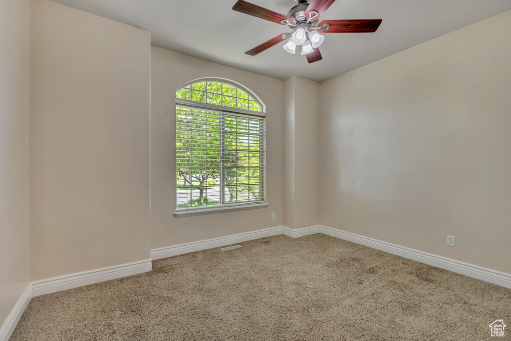 Empty room featuring carpet floors, healthy amount of natural light, baseboards, and ceiling fan