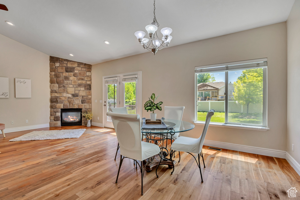 Dining room with plenty of natural light, light wood finished floors, a chandelier, baseboards, and vaulted ceiling
